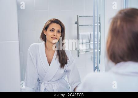 Schöne junge Frau, die in den Spiegel Stockfoto