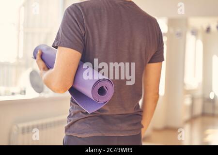 Junger Mann im Hemd mit Yogamatte Stockfoto