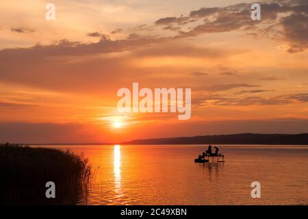 Schöner Sonnenuntergang über dem Plattensee mit Silhouetten von Anglern und Schilf Stockfoto