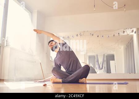 Bärtiger junger Mann, der im Yoga-Studio trainiert Stockfoto