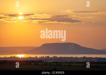 Sonnenuntergang über dem Plattensee und Badacsony Berg mit nebligen Wäldern und Weinbergen im Vordergrund Stockfoto