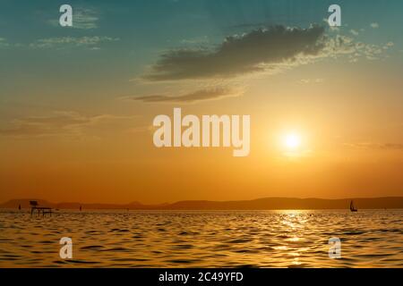 Schöner Sonnenuntergang über dem Plattensee mit Silhouetten von Segelboot und Angler Pier in Ungarn Stockfoto