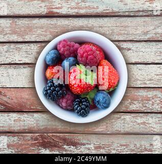 Draufsicht. Früchte und Beeren in Schale auf Holzhintergrund. Reife Himbeeren, Erdbeeren, Brombeeren und Heidelbeeren. Hintergrund der Mischung Früchte mit Stockfoto