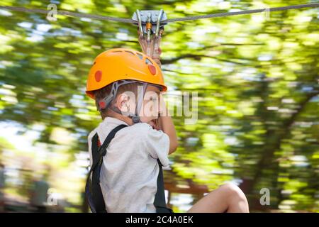 Junge rutscht nach unten Seil befestigt zwischen Bäumen Stockfoto