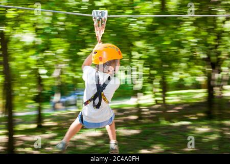 Junge rutscht nach unten Seil befestigt zwischen Bäumen Stockfoto