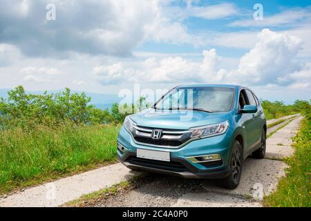 Mnt. runa, ukraine - 22. JUN 2019: Cyan honda cr-V suv auf der Bergstraße. Erkunden Sie das Wildnis-Konzept. Grat in der Ferne. Sonniges Wetter. clo Stockfoto