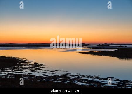 Ein dramatischer Sonnenuntergang über dem Wasser, von der Nähe des Causeway zwischen Benbecula und North Uist gesehen Stockfoto