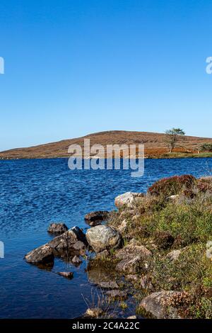 Blick über Loch Druidibeg auf der hebridischen Insel South Uist, mit einem blauen Himmel über dem Meer Stockfoto