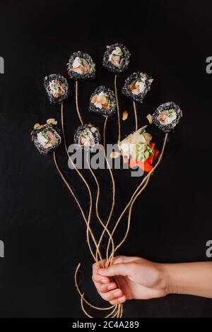 Frau Hand hält sushiu Ballons auf schwarzem Hintergrund gesetzt. Stockfoto