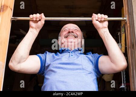 Älterer Mann, der an der horizontalen Stange hochzieht. Stockfoto