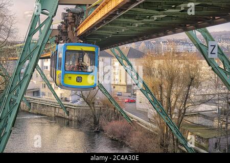 Ein Zug der Wuppertaler Schwebebahn fliegt über den Fluss. Dieses System ist einzigartig auf der Welt. Stockfoto