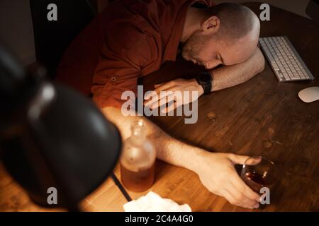 Blick aus der Perspektive eines reifen Mannes, der nach einem Alkoholgetränk am Tisch schläft Stockfoto