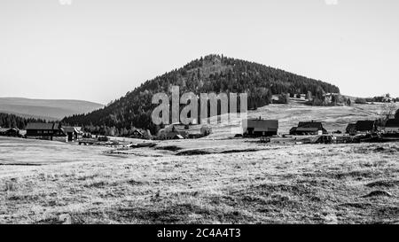 Berg Bukovec oberhalb des Dorfes Jizerka im Isergebirge, Tschechische Republik. Klarer sonniger Tag. Schwarzweiß-Bild. Stockfoto