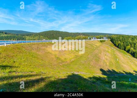 Josefuv Dul-Staudamm, Erdstaudamm im Isergebirge mit Asphaltstraße auf der Spitze, Tschechische Republik. Sonniger Sommertag. Stockfoto