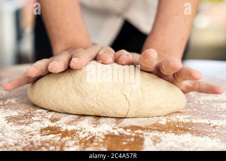 Frau, die mit ihren Händen den Teig knetet Stockfoto