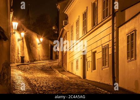 Schmale gepflasterte Straße in alten mittelalterlichen Stadt mit beleuchteten Häusern von Vintage-Straßenlampen, Novy svet, Prag, Tschechische Republik. Nachtaufnahme. Stockfoto