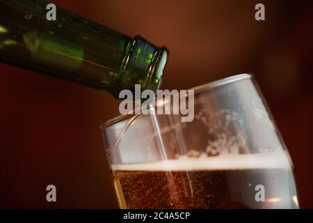 Nahaufnahme von kaltem Bier im Glas, das aus der Flasche gegossen wird Stockfoto
