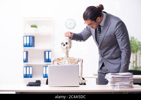 Junge Angestellte und Skelett im Büro Stockfoto