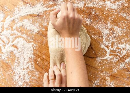 Frau, die mit ihren Händen den Teig knetet Stockfoto