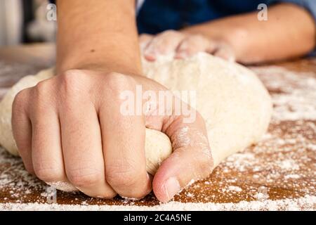 Frau, die mit ihren Händen den Teig knetet Stockfoto