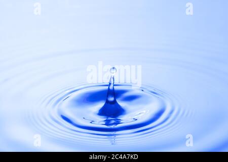 Wassertropfen fallen Aufprall mit Wasseroberfläche. Verursacht Ringe auf Wasseroberfläche. Stockfoto