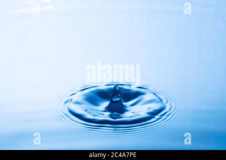 Wassertropfen fallen Aufprall mit Wasseroberfläche. Verursacht Ringe auf Wasseroberfläche. Stockfoto