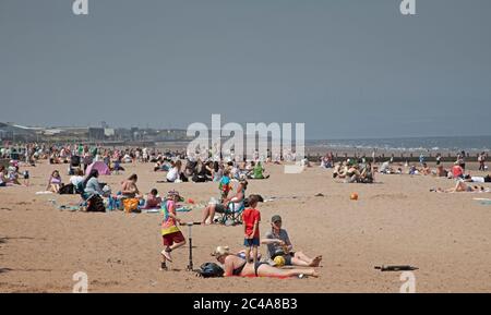 Portobello, Edinburgh, Schottland, Großbritannien. 25. Juni 2020. 2. Tag sehr heißer Witterung, obwohl es kühler war, mit einer kühlen Brise zu beginnen, als es begann, Dampf aufzuheizen, begann aus dem nassen Sand zu steigen und verursachte einen Dunst, die Temperatur erreichte 20 Grad zur Mittagszeit, mehr Leute früher als gestern, Hoffnungsvollusend Sonnenschirm, um sie vor den höheren UV-Strahlen zu schützen, die Wettervorhersagen ungefähr warnen. Stockfoto