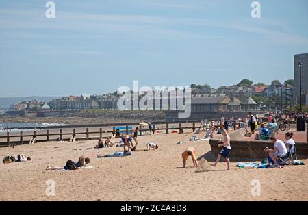 Portobello, Edinburgh, Schottland, Großbritannien. 25. Juni 2020. 2. Tag sehr heißer Witterung, obwohl es kühler war, mit einer kühlen Brise zu beginnen, als es begann, Dampf aufzuheizen, begann aus dem nassen Sand zu steigen und verursachte einen Dunst, die Temperatur erreichte 20 Grad zur Mittagszeit, mehr Leute früher als gestern, Hoffnungsvollusend Sonnenschirm, um sie vor den höheren UV-Strahlen zu schützen, die Wettervorhersagen ungefähr warnen. Stockfoto