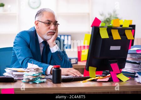 Alter Mitarbeiter im Büro in widersprüchlichen Prioritäten Konzept Stockfoto