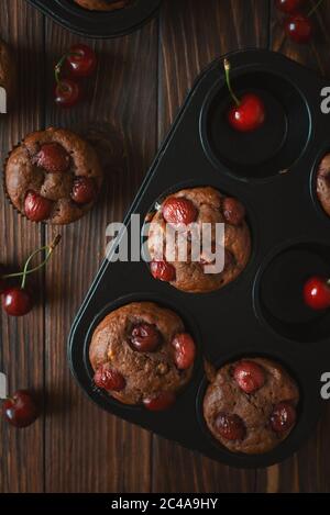 Gesunde vegane BananenkirschMuffins mit frischen Beeren auf braunem Holzhintergrund. Draufsicht. Sommeressen Stockfoto