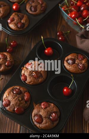 Gesunde vegane BananenkirschMuffins mit frischen Beeren auf braunem Holzhintergrund. Draufsicht. Sommeressen Stockfoto