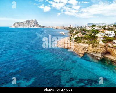 Luftaufnahme Benissa oder Benisa felsige Küste, Blick auf den Penyal d'IFAC Naturpark des Calpe Resorts. Mittelmeer türkisfarbenes Wasser wolkiger Himmel sonnig Stockfoto