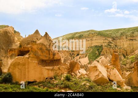 Hoodoos von Kappadokien. Zeltfelsen, die von Wind und Wasser im Laufe der Zeit in der Geschichte geschnitzt wurden. Wolken und Gras. Höhlen von Kappadokien, Nevsehir / Türkei Stockfoto