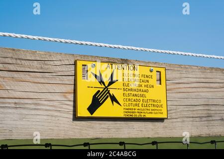 Schild auf Holzzaun warnt Menschen vor elektrischen Zaun. Green Tye, Much Hadham, Hertfordshire. GROSSBRITANNIEN Stockfoto