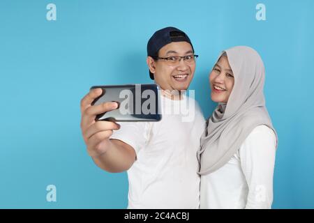 Portait von glücklich asiatischen muslimischen Paar macht Selfie und lächelnd, Mann und Frau umarmt voller Liebe, Familienkonzept Stockfoto