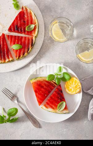 Gegrillte Wassermelonenscheiben mit Zitrone und Basilikum. Sommerdessert Stockfoto