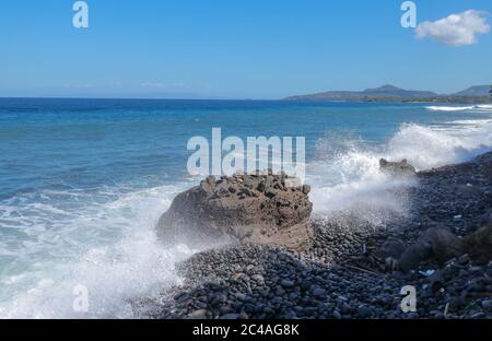 Die Wellen brechen an einem steinigen Strand und bilden einen großen Spray. Großwellen-Crash gegen die Felsen während eines Sturms in den Tropen. Starke Wellen Stockfoto