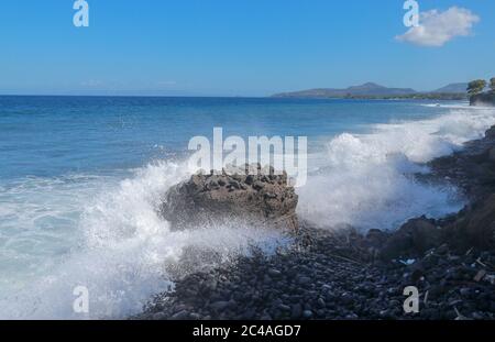 Die Wellen brechen an einem steinigen Strand und bilden einen großen Spray. Großwellen-Crash gegen die Felsen während eines Sturms in den Tropen. Starke Wellen Stockfoto