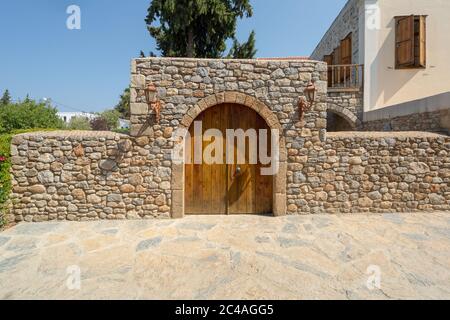 Alte lackierte Holztür und Steinwand mit Laternen auf beiden Seiten. Alter mediterraner Stil von Datca, Türkei. Stockfoto