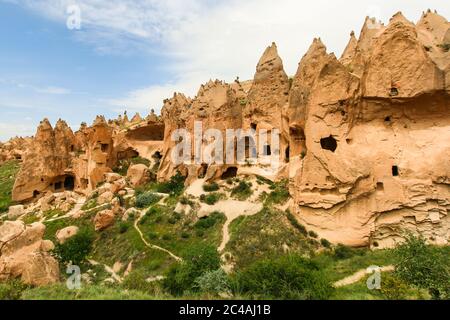 Hoodoos von Kappadokien. Zeltfelsen, die von Wind und Wasser im Laufe der Zeit in der Geschichte geschnitzt wurden. Wolken und Gras. Höhlen von Kappadokien, Nevsehir / Türkei Stockfoto