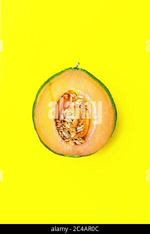 Honigmelone oder Cantaloupe Cucumis melo. Eine Hälfte der japanischen Melone auf gelbem Hintergrund. Sommerliche Früchte. Gesunde Ernährung Konzept. Draufsicht Stockfoto