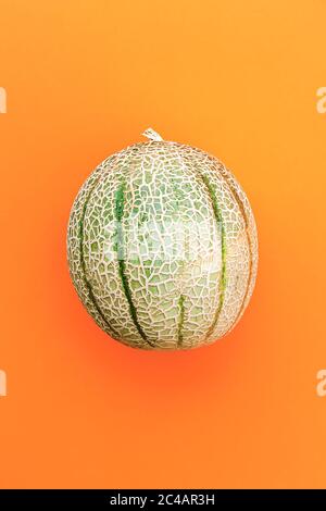 Honigmelone oder Cantaloupe Cucumis melo. Japanische Melone auf orangefarbenem Hintergrund. Sommerliche Früchte. Gesunde Ernährung Konzept. Draufsicht. Stockfoto