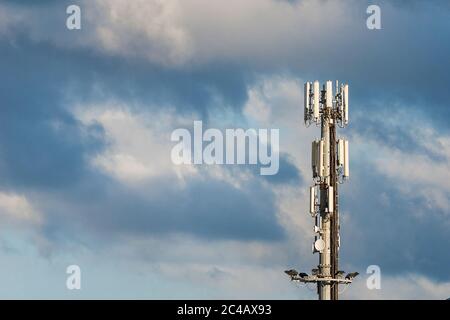 Elektromagnetische Strahlung. Telekommunikationsturm mit 5G- und 4G-Antennen zwischen den Wolken (mit Kopierplatz) Stockfoto