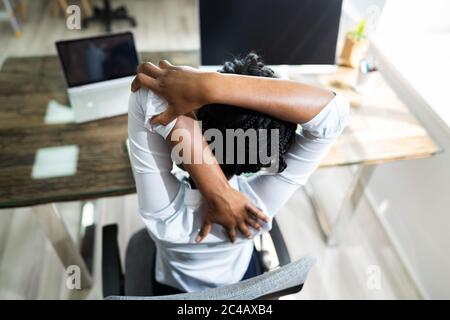 Schwarze Frau Streckt Sich Im Büro Am Schreibtisch Stockfoto