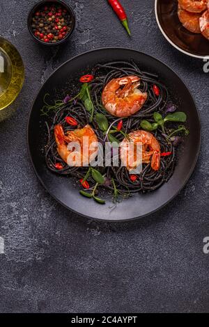 Italienische Pasta schwarze Spaghetti mit Garnelen und Microgreens, Draufsicht. Stockfoto