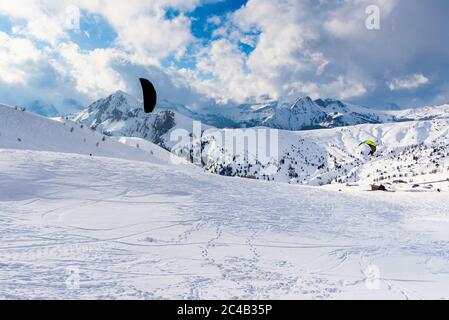 Atemberaubende schneebedeckte Berglandschaft mit Menschen Snowkiten in den Europäischen Alpen an einem sonnigen Wintertag Stockfoto