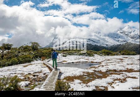 Wanderer auf dem Naturpfad, Key Summit, Snowy Mountain View, Routeburn Track, Fiordland National Park, Te Anau, Southland, South Island, Neuseeland Stockfoto
