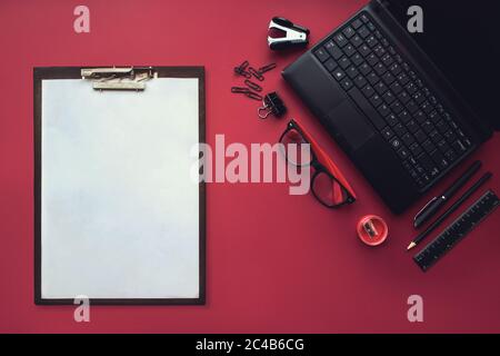 Set aus schwarzen Schreibwaren-Elementen mit Plastiktablett und weißem Blatt Papier auf dem roten Hintergrund. Draufsicht. Konzept der neuen Möglichkeiten, Ideen, un Stockfoto