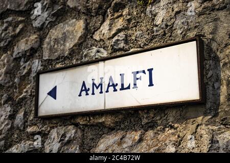 Nahaufnahme eines alten Straßenschildes von Ravello, der die Richtung nach Amalfi anzeigt. In der Provinz Salerno, an der Amalfiküste. Stockfoto