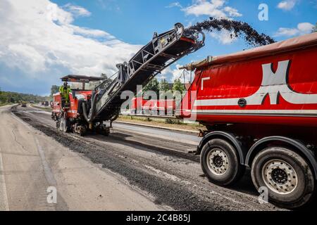 Straßenbau, Kaltfräsmaschine entfernt alte Asphaltschicht und füttert den LKW mit gefrästem Asphalt, Rehabilitation der Autobahn A3 dazwischen Stockfoto